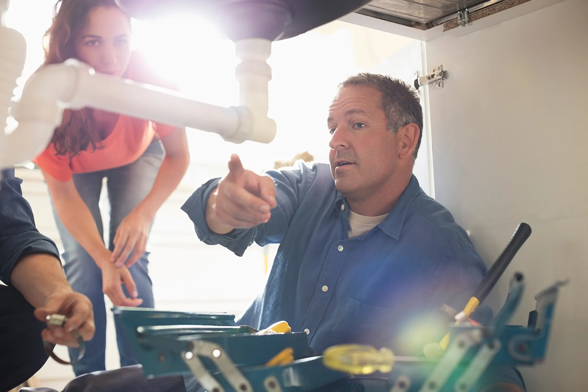 Plumber explaining an under sink repair process to residential homeowner