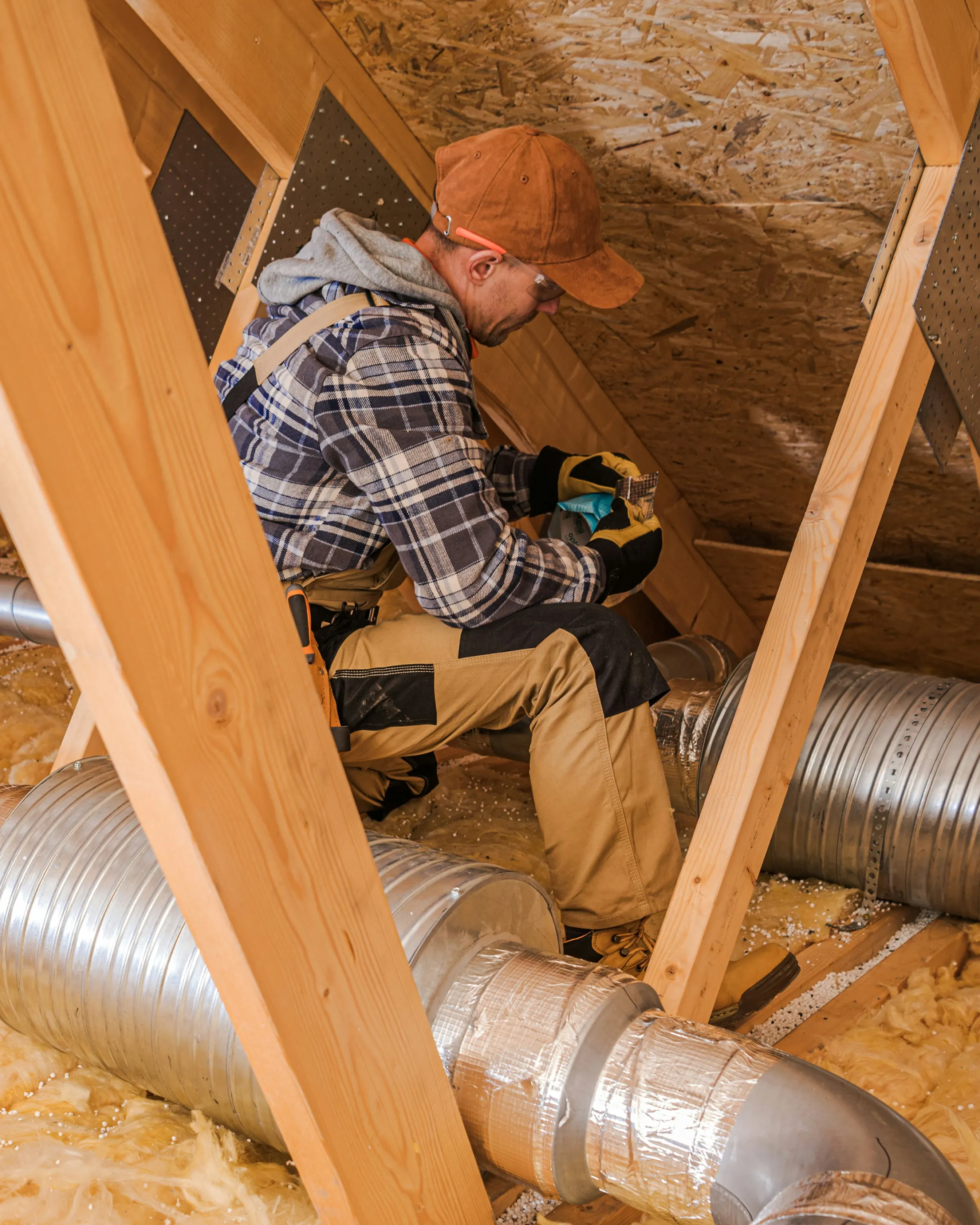 Technician working in an attic near ductwork.