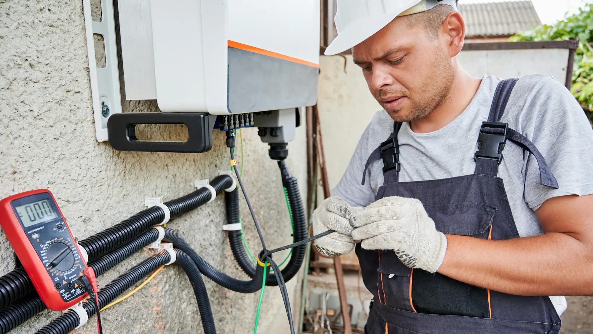 Electrical technician working on an exterior solar inverter