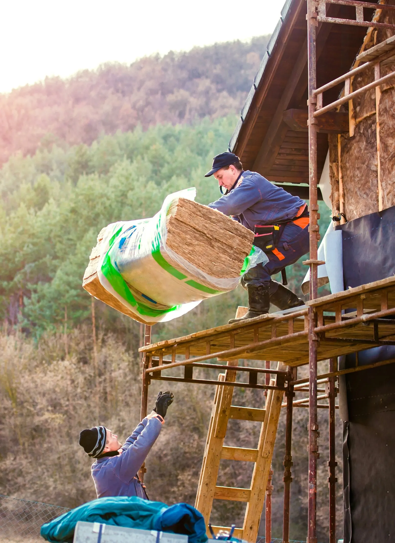 Insulation crew moving material into a home exterior