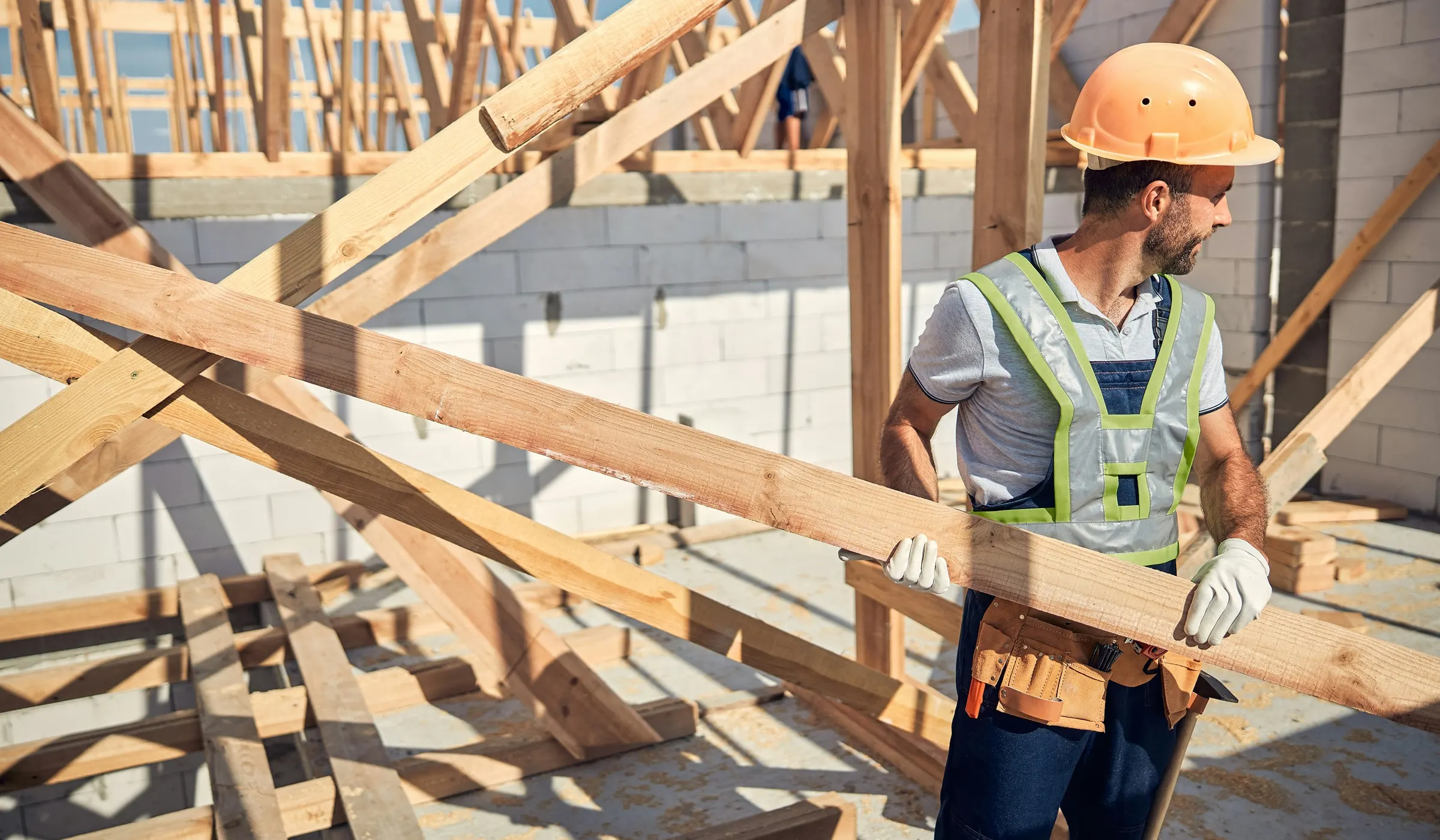 Trades operator carrying lumber through a framed roof structure